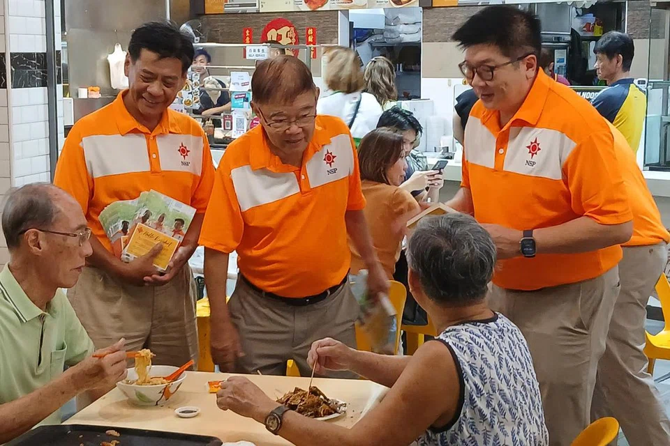 Presiden Parti Perpaduan Nasional (NSP), Encik Reno Fong (berdiri, kanan) dan Naib Presiden NSP, Encik Mohd Ridzwan Mohammad (berdiri, kiri) bersama pasukan NSP di Tampines Street 21 pada 24 April.