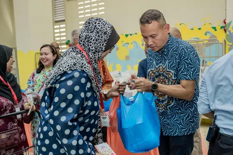 AGIH DAGING KORBAN: Mayor Majlis Pembangunan Masyarakat (CDC) South East, Encik Mohd Fahmi Aliman (kanan) mengagihkan daging korban kepada penerima bantuan di Rumah Peralihan Pertapis pada Sabtu.