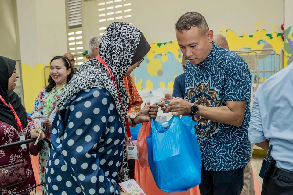 AGIH DAGING KORBAN: Mayor Majlis Pembangunan Masyarakat (CDC) South East, Encik Mohd Fahmi Aliman (kanan) mengagihkan daging korban kepada penerima bantuan di Rumah Peralihan Pertapis pada Sabtu.