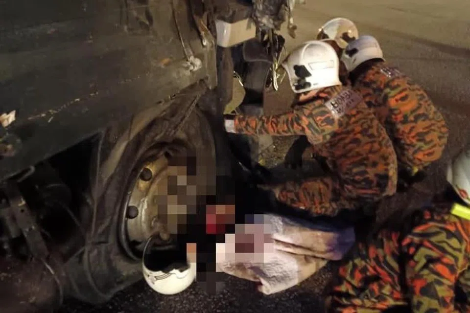 TRAGEDI MALANG: Anggota bomba dari Balai Bomba dan Penyelamat Iskandar Puteri mengeluarkan mayat penunggang motosikal yang tersepit di bawah lori dalam kemalangan membabitkan lima kenderaan di Plaza Tol Tanjung Kupang, Gelang Patah, Johor, kira-kira 6 pagi pada 22 Disember.