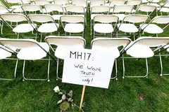 Satu tanda bantahan berhampiran deretan bangku sedang keluarga mangsa MH17 mengatur bangku kosong bagi setiap tempat duduk dalam pesawat dalam satu bantahan di luar Kedutaan russia di The Hague, Netherlands, pada 8 Mac. 