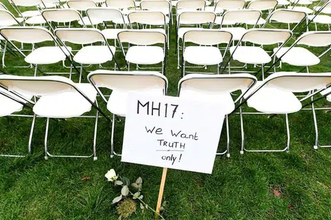 Satu tanda bantahan berhampiran deretan bangku sedang keluarga mangsa MH17 mengatur bangku kosong bagi setiap tempat duduk dalam pesawat dalam satu bantahan di luar Kedutaan russia di The Hague, Netherlands, pada 8 Mac. 