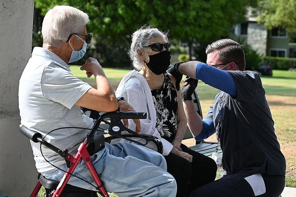AMBIL DOS PENGGALAK: Jururawat Kevin Grellman memberi dos penggalak ketiga vaksin Pfizer Covid-19 kepada Cik Armida Gomez, 81 tahun, sementara suaminya Jose Gomez, 80 tahun, menunggu gilirannya di Pasadena, California, bulan lalu. - Foto AFP