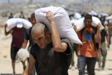 Rakyat Palestin mengangkat bekalan bantuan yang masuk ke Gaza melalui Israel, di Beit Lahia, di utara Gaza pada 1 Ogos 2025.