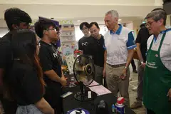 Menteri Kanan, Encik Lee Hsien Loong (dua dari kanan), berinteraksi dengan penuntut tahun pertama jurusan Robotik dan Mekatronikdi Politeknik Nanyang (NYP) Nathan Ian, 17 tahun (tiga dari kiri) semasa lawatannya ke reruai ‘Repair Kopitiam’ di acara Eco Fest anjuran bersama pertubuhan akar umbi Teck Ghee dan NYP berlangsung di Kelab Masyarakat Teck Ghee pada 3 November.