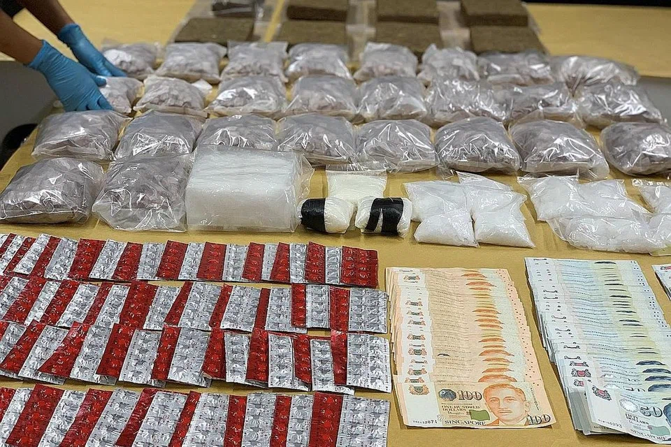 HASIL RAMPASAN: Pegawai Biro Narkotik Pusat (CNB) menunjukkan hasil rampasan, merangkumi wang tunai dan pelbagai jenis dadah termasuk 14kg heroin, daripada operasi yang dijalankan pada 11 November 2020. Keseluruhan dadah yang dirampas bernilai sekitar $2 juta. - Foto CNB