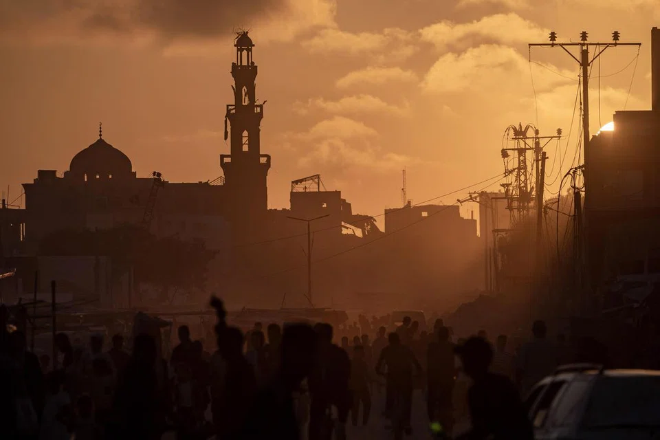 Penduduk Palestin berjalan pada waktu matahari terbenam di jalan yang musnah di kem pelarian Khan Younis, selatan Jaluran Gaza, pada 11 Jun sedang mereka mengharapkan perang di Gaza segera tamat untuk memulakan kehidupan baru.