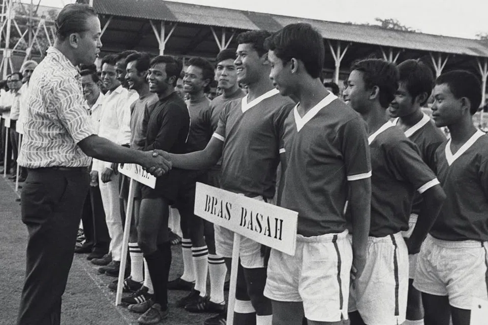 PENGGEMAR SUKAN: Sebagai Menteri yang bertanggungjawab bagi Sukan, Encik Othman bersalam dengan beberapa peserta di acara pembukaan kejohanan bola sepak antara kawasan undi di Stadium Jalan Besar. 