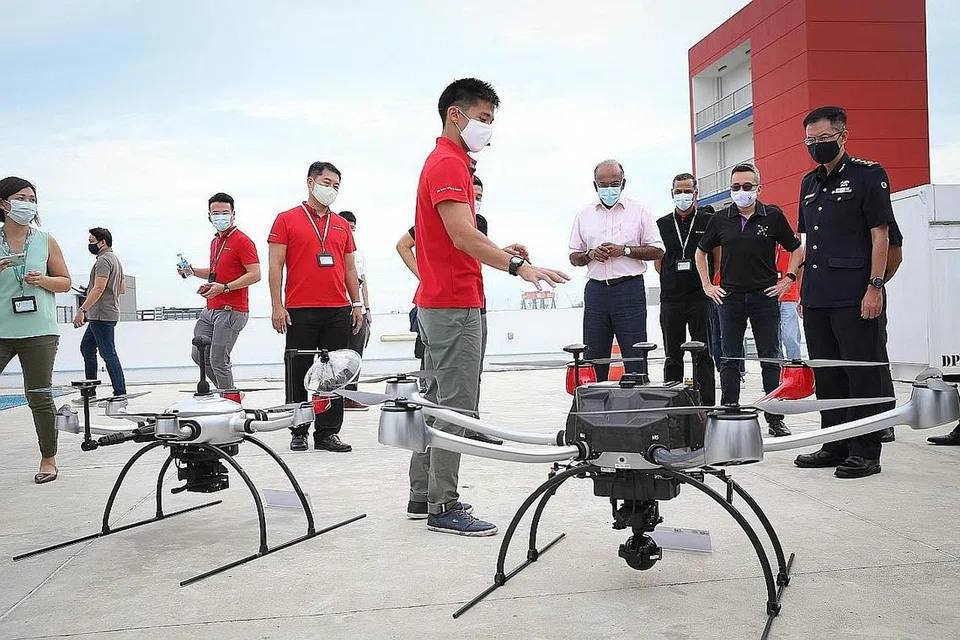 DETIK BERSEJARAH: Encik K Shanmugam (empat dari kanan) menyaksikan penerbangan sulung jarak jauh di Luar Garisan Penglihatan Visual (BVLOS) bagi kenderaan udara tanpa pemandu (UAV) HTX di Balai Bomba Tuas View semalam. - Foto BH oleh ONG WEE JIN