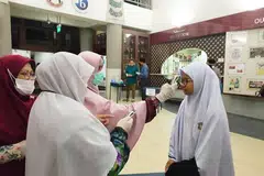 AWASI KEADAAN: Kakitangan Madrasah Aljunied Al-Islamiah sedang mengambil suhu badan pelajar secara beramai-ramai sebelum kelas bermula. - Foto FACEBOOK/ MADRASAH ALJUNIED AL-ISLAMIAH
