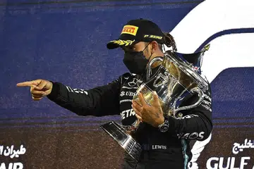 RANGKUL TROFI: Pemandu Mercedes Lewis Hamilton merangkul trofi Grand Prix Bahrain di Sakhir dengan mencatat kemenangan ke-11 musim ini dengan pemandu Red Bull Max Verstappen dan Alexander Albon di tempat kedua dan ketiga. - Foto AFP
