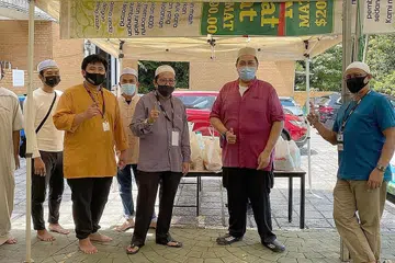 INGIN TERUS MEMBANTU: Antara sukarelawan Masjid Al-Amin yang turut membantu menjual habuan amal kepada jemaah selepas solat Jumaat. - Foto MASJID AL-AMIN