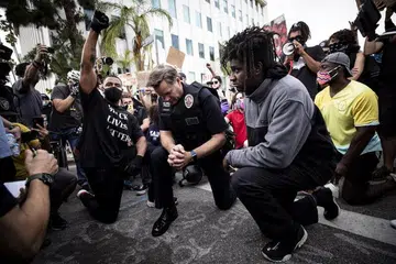 DUDUK SAMA RENDAH: Ketua Polis Daerah Los Angeles (LAPD), Komander Cory Palka (tengah) turut sama berlutut dengan para penunjuk perasaan bersebelahan rumah datuk bandar Los Angeles, Encik Eric Garcetti, di California semalam, sedang penunjuk perasaan berhimpun mengadakan bantahan atas kematian Encik George Floyd, yang disebabkan oleh keganasan polis pada 25 Mei lalu. 