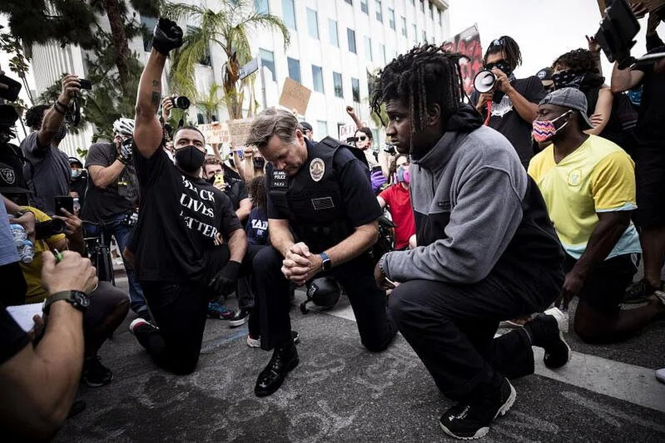 DUDUK SAMA RENDAH: Ketua Polis Daerah Los Angeles (LAPD), Komander Cory Palka (tengah) turut sama berlutut dengan para penunjuk perasaan bersebelahan rumah datuk bandar Los Angeles, Encik Eric Garcetti, di California semalam, sedang penunjuk perasaan berhimpun mengadakan bantahan atas kematian Encik George Floyd, yang disebabkan oleh keganasan polis pada 25 Mei lalu. 