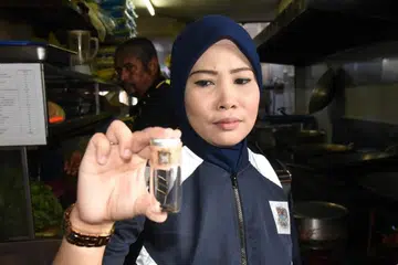 MENJIJIKKAN: Pegawai penguatkuasa Majlis Bandaraya Pulau Pinang menunjukkan najis tikus yang ditemui di restoran di Lebuh Chulia, Georgetown, Pulau Pinang. 