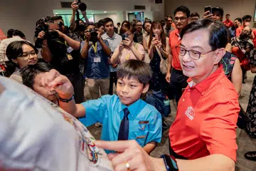SENI DIKAGUMI: Muhammmad Rizq Daniyal Muhammad Lufti (kiri) memperlihatkan karyanya kepada Encik Heng Swee Keat dalam satu acara diadakan pada 15 Jun lalu. 