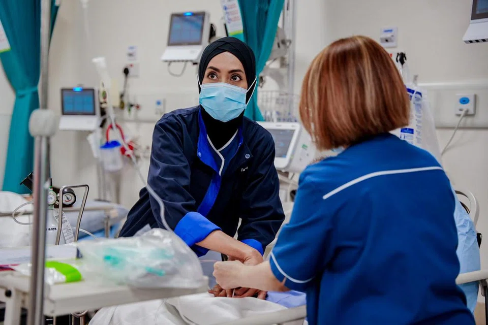 Jururawat staf kanan, Cik Siti Farhana Jumari (kiri), merawat seorang pesakit bersama rakan setugas, Cik Rawaida Mohamed Aron (kanan). 