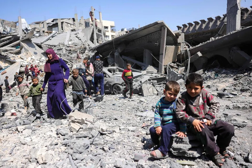Para penduduk melintasi puing-puing bangunan yang menyembah bumi selepas Israel melancarkan serangan udara di Jabalia, utara Gaza, pada 18 Mac.