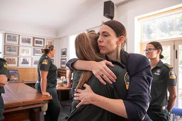 RASA SEDIH: Perdana Menteri New Zealand, Cik Jacinda Ardern memeluk salah seorang anggota penyelamat yang pertama tiba bagi membantu mangsa letusan gunung berapi di White Island di Balai Bomba Whakatane. - Foto AFP