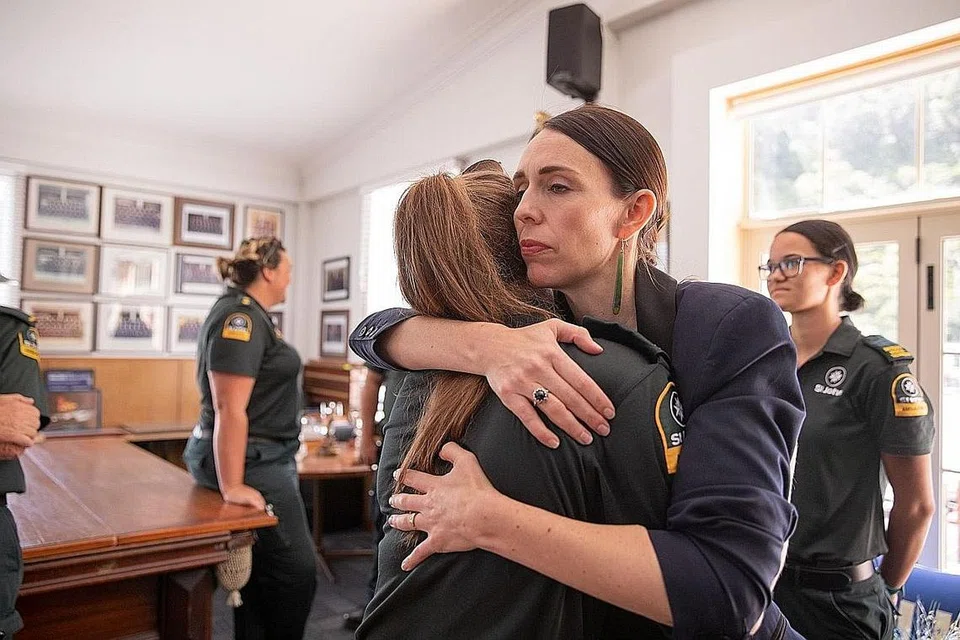 RASA SEDIH: Perdana Menteri New Zealand, Cik Jacinda Ardern memeluk salah seorang anggota penyelamat yang pertama tiba bagi membantu mangsa letusan gunung berapi di White Island di Balai Bomba Whakatane. - Foto AFP