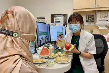 NASIHAT PILIHAN PEMAKANAN YANG BAIK: Cik Rachel Tan sedang memberi panduan tentang makanan sihat kepada seorang pesakit. - Foto TTSH
