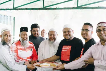 JAMU PEKERJA ASING: Encik Mohamed Rafeeq (dua dari kiri), Ustaz Zahid Zin (tiga dari kanan) dan Encik Mohamed Shah Reza (dua dari kanan) merupakan antara individu yang menjayakan acara 'Thank you, Bhaiya' untuk menjamu 1,000 pekerja asing di Masjid Al-Firdaus semalam. - Foto PINNACLE STUDIOS