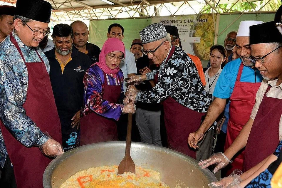 DEMI AMAL: Presiden Halimah bersama suaminya, Encik Mohamed Abdullah Alhabshee (tengah), menggaul nasi beriani sebagai melancarkan acara Beriani Amal Cabaran Presiden di Masjid Khalid. Turut serta (barisan depan, dari kiri) ialah Mufti Dr Mohd Fatris Bakaram, Encik Allaudin Mohamed, dan Encik Masagos Zulkifli. - Foto BH oleh MUIS