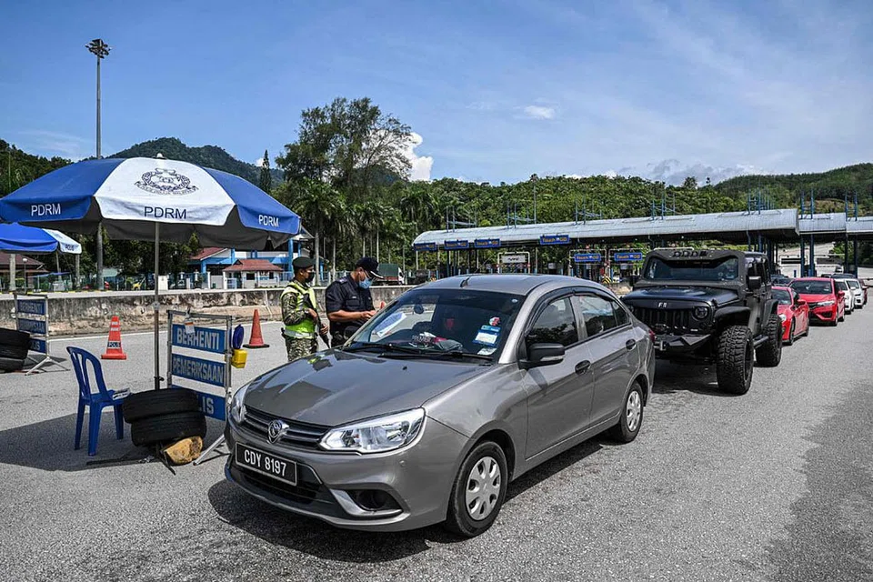 TINGKAT PEMERIKSAAN: Seorang anggota polis sedang memerikan dokumen perjalanan seorang pemandu di satu jalan raya utama baru-baru ini. Pihak berkuasa Malaysia telah mengarahkan semua jabatan dan agensi penguatkuasaan di bawahnya untuk meningkatkan bilangan operasi pemantauan demi membendung penularan Covid-19. - Foto AFP