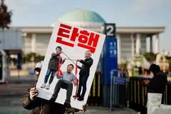 Seorang penunjuk perasaan memegang sepanduk menuntut pemecatan Presiden Korea Selatan, Yoon Suk Yeol, yang mengisytiharkan undang-undang tentera sebelum menarik balik arahan itu beberapa jam kemudian, di hadapan Perhimpunan Kebangsaan di Seoul, Korea Selatan, 9 Disember. 