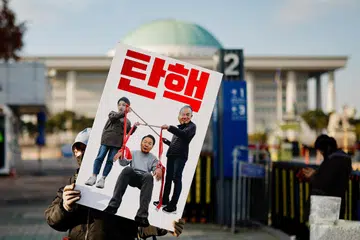 Seorang penunjuk perasaan memegang sepanduk menuntut pemecatan Presiden Korea Selatan, Yoon Suk Yeol, yang mengisytiharkan undang-undang tentera sebelum menarik balik arahan itu beberapa jam kemudian, di hadapan Perhimpunan Kebangsaan di Seoul, Korea Selatan, 9 Disember. 