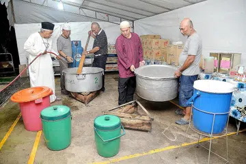 SEMANGAT KAMPUNG: Penduduk yang tinggal berdekatan Masjid Pertempatan Melayu Sembawang gigih merebus daging dengan dibantu, antaranya oleh pengerusi masjid, Encik Amin Abu Latip (kiri) untuk memasak dalca bagi juadah berbuka puasa. - Foto M.O. SALLEH