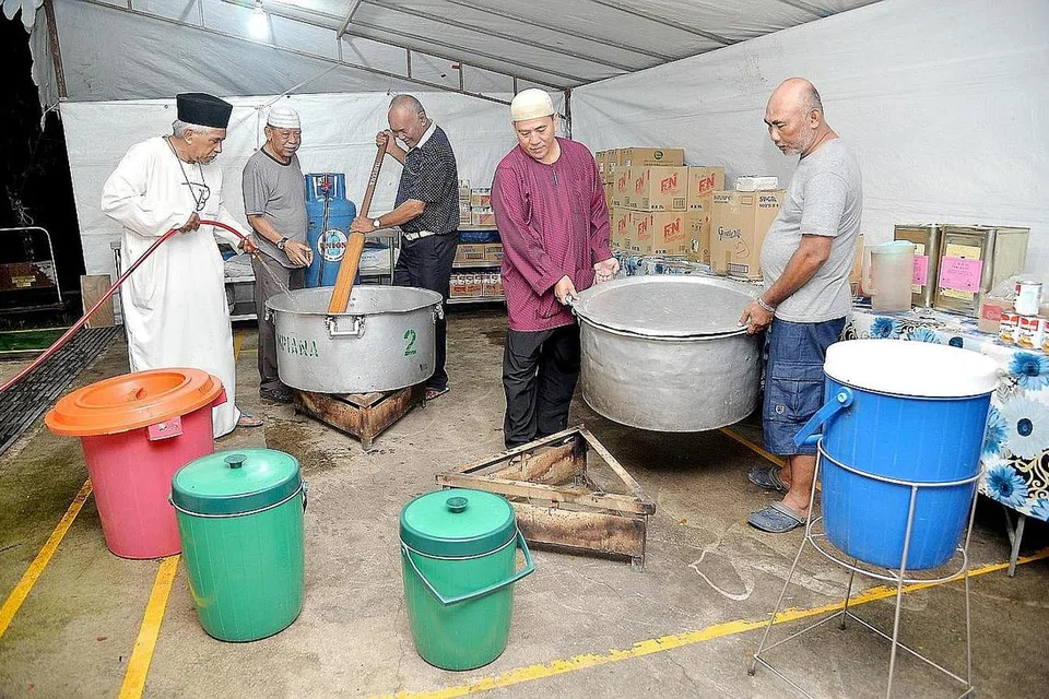 SEMANGAT KAMPUNG: Penduduk yang tinggal berdekatan Masjid Pertempatan Melayu Sembawang gigih merebus daging dengan dibantu, antaranya oleh pengerusi masjid, Encik Amin Abu Latip (kiri) untuk memasak dalca bagi juadah berbuka puasa. - Foto M.O. SALLEH