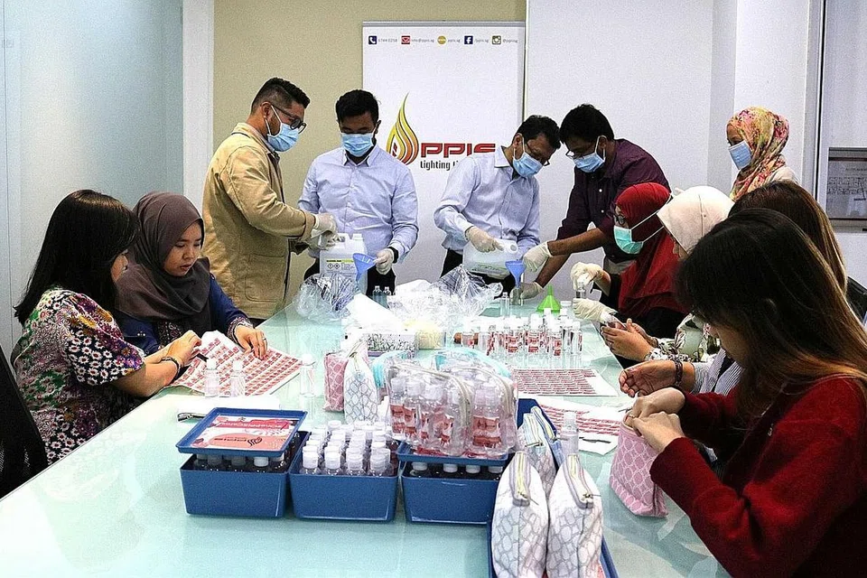 BERGOTONGROYONG: Kakitangan ibu pejabat PPIS membungkus sanitiser tangan ke dalam botol untuk diagih kepada rakan kerja di barisan depan. - Foto PPIS