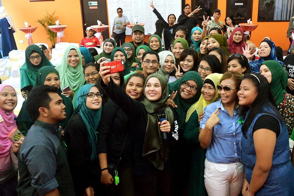PEMINAT GHAIRAH: Peminat Singapura berpeluang bertemu dan berselfie dengan pelakon popular Malaysia, Emma Maembong (memegang telefon bimbit) dalam acara sesi 'Sepetang Bersama Emma Maembong' Sabtu lalu di bilik pameran 'Doktor Kereta' di Woodlands.. - Foto KHALID BABA