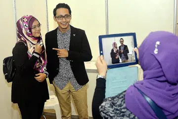 KIAN POPULAR: Penyanyi Sufian Suhaimi yang terkenal dengan lagu Terakhir kelihatan bergambar bersama seorang peminatnya semasa beliau berada di Singapura bagi acara Pameran The Great Wedding Affair & The Big Year End Sale baru-baru ini. - Foto KHALID BABA