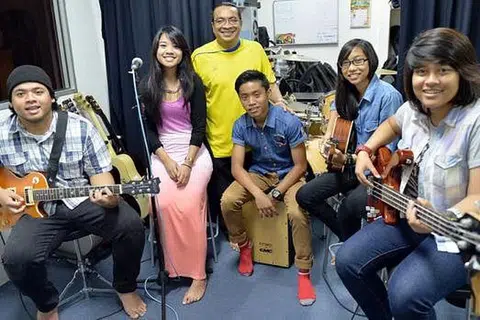 KUGIRAN BELIA: Bekas pemain gitar kumpulan Lovehunters, Encik Moliano Rasmadi (berbaju kuning), bersama para belia (dari kiri) Faiz Ridhwan Roswani, Roze Syazalin Roswani, Adli Nur Hakim Ariffin, Siti Norsyafiqah Mohamed Rashid dan Nurul Syafiqah Ryhme, yang mengikuti kelas bimbingan muzik Malay Youth Performing Art (MyPart). - Foto KHALID BABA
