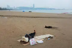 KELEMBAPAN EKONOMI: Seorang lelaki tidur di pantai di Pattaya, Thailand, yang selalunya padat dengan pelancong, menyusuli penularan penyakit koronavirus, semasa gambar dirakamkan pada 26 April lalu.