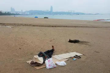 KELEMBAPAN EKONOMI: Seorang lelaki tidur di pantai di Pattaya, Thailand, yang selalunya padat dengan pelancong, menyusuli penularan penyakit koronavirus, semasa gambar dirakamkan pada 26 April lalu.