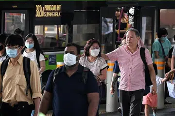 MASIH DIGUNAKAN: Beberapa penumpang di Pusat Tukaran Bas Punggol (gambar atas) dan penumpang MRT masih lagi menggunakan pelitup pada 13 Februari. - Foto-foto ST