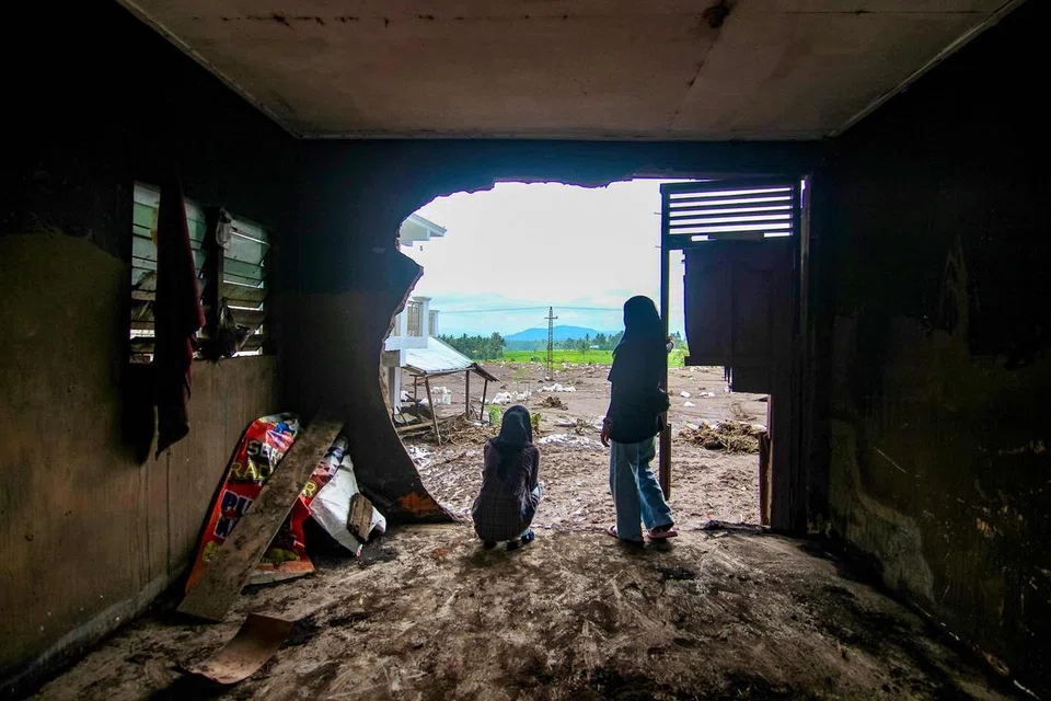 Dua wanita meninjau kesan banjir yang telah memusnahkan rumah mereka di kampung Limo Kaum, di Tanah Datar, Sumatera Barat, Indonesia.
