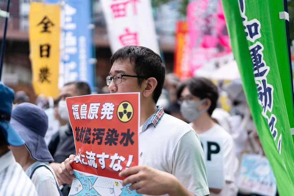 BANTAHAN BESAR-BESARAN: Orang ramai memegang sepanduk dalam protes menentang pelepasan air yang disyaki masih mengandungi radioaktif dari stesen kuasa nuklear di Fukushima.