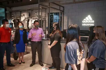 TINJAU SEKTOR RUNCIT: Encik Zaqy Mohamad bersembang dengan pengurus kedai Cik Gan Shiying dalam kunjungannya ke stor Adidas di Jewel Changi Airport. - Foto BH oleh KEVIN LIM 