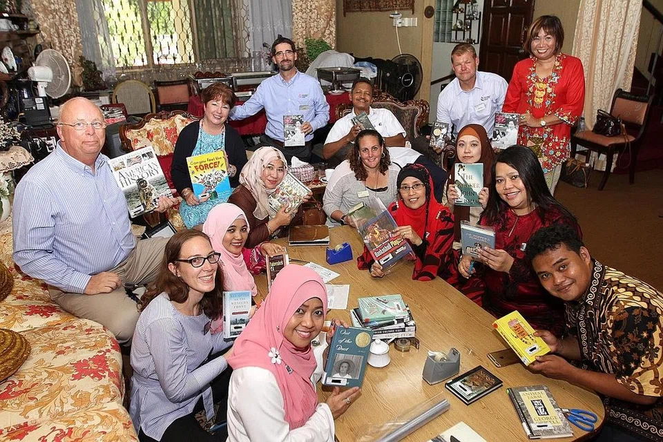 TABUR BAKTI, DERMA BUKU: Beberapa bekas pelajar Sekolah Menengah Yusof Ishak (YISS) dan kakitangan Sekolah Masyarakat Antarabangsa (ICS) membalut buku sumbangan ICS kepada perpustakaan YISS sempena projek '25 Acts of Kindness'. - Foto SHAHRIYA YAHAYA