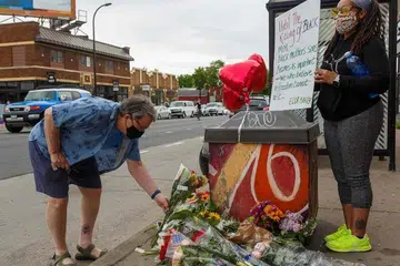 MENGINGATI MANGSA: Seorang lelaki meletakkan jambangan bunga sambil diperhatikan seorang wanita di tempat berlaku kejadian di Minneapolis, Minnesota, Amerika Syarikat. Mangsa, Encik George Floyd, meninggal dunia semasa ditahan polis. 