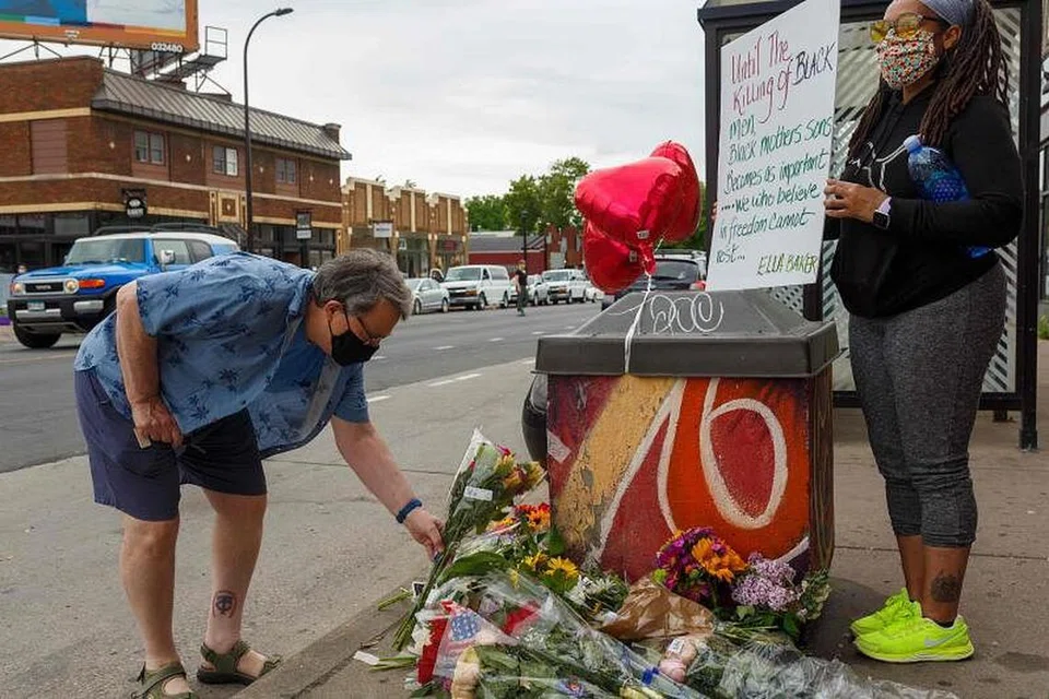 MENGINGATI MANGSA: Seorang lelaki meletakkan jambangan bunga sambil diperhatikan seorang wanita di tempat berlaku kejadian di Minneapolis, Minnesota, Amerika Syarikat. Mangsa, Encik George Floyd, meninggal dunia semasa ditahan polis. 