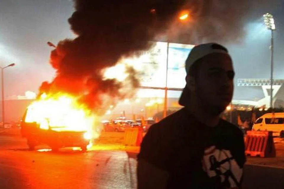 KERETA POLIS DIBAKAR: Dalam kejadian kelmarin, belia ini dilihat berjalan di depan sebuah kereta ronda polis yang dibakar. - Foto REUTERS 