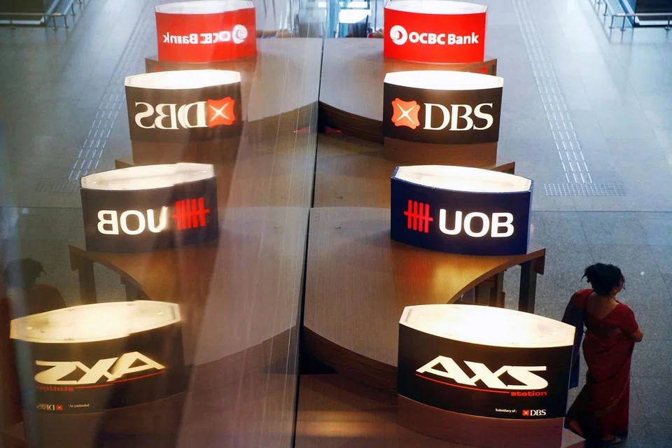 PENDEDAHAN TERKAWAL: Seorang wanita berjalan melalui ATM UOB, DBS dan OCBC. Mutu aset tiga bank itu terjejas disebabkan pendedahan pinjamannya dalam industri minyak dan gas. - Foto REUTERS