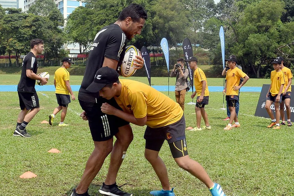 BERI BIMBINGAN: Pemain New Zealand, Sione Molia (kiri), cuba dijatuhkan oleh salah seorang pemain muda Sekolah Anglo-Chinese (Bebas) semasa satu klinik ragbi yang dianjurkan petang semalam. Sekitar 30 pemain sekolah berkenaan berpeluang menimba pengalaman di klinik anjuran penaja pasukan All Blacks - AIG dan Air New Zealand - itu yang diadakan sempena Ragbi Tujuh Sepasuk Dunia hujung minggu ini. - Foto TAUFIK A. KADER 