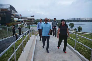 KEMUDAHAN BARU: Encik Shanmugam (depan, kiri) meneliti rumah kelab baru di Bedok Reservoir semalam. Rumah kelab baru itu, yang dibuka kepada anggota kerahan Perkhidmatan Negara (NSmen) Home Team dan orang awam, menampilkan pelbagai kemudahan seperti pusat kembara air Aqua Adventure dan 10 villa dua tingkat. - Foto BH oleh GIN TAY