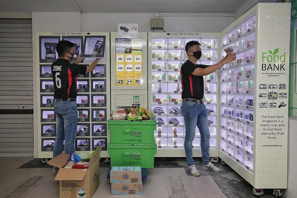 PROJEK MASYARAKAT: Penduduk mengisi bekalan makanan di mesin layan diri yang terdapat di kolong Blok 158 Toa Payoh Lorong 1 bagi keperluan golongan memerlukan. - Foto BH oleh KEVIN LIM